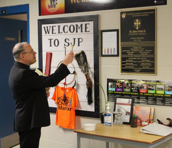 Most Reverend Archbishop Damphousse blesses the new plaque at St. John Paul II Catholic School.